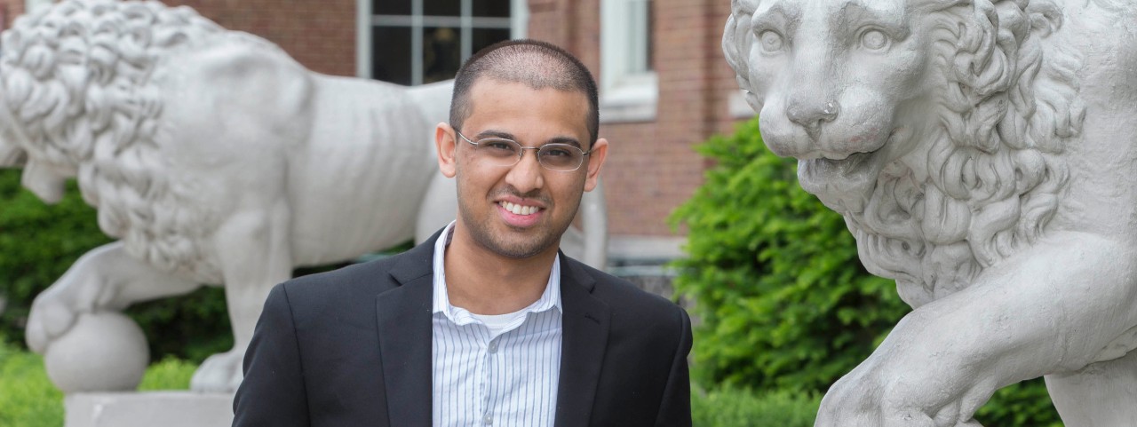 Student Chinmay Bakshi stands by the stone  lions outside outside Arts & Sciences Hall, University of Cincinnati