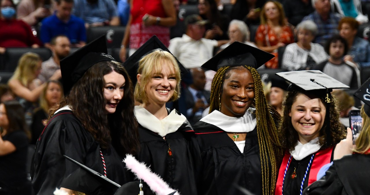 Students pose for a photo in their caps and gowns on the floor of Fifth Third Arena.