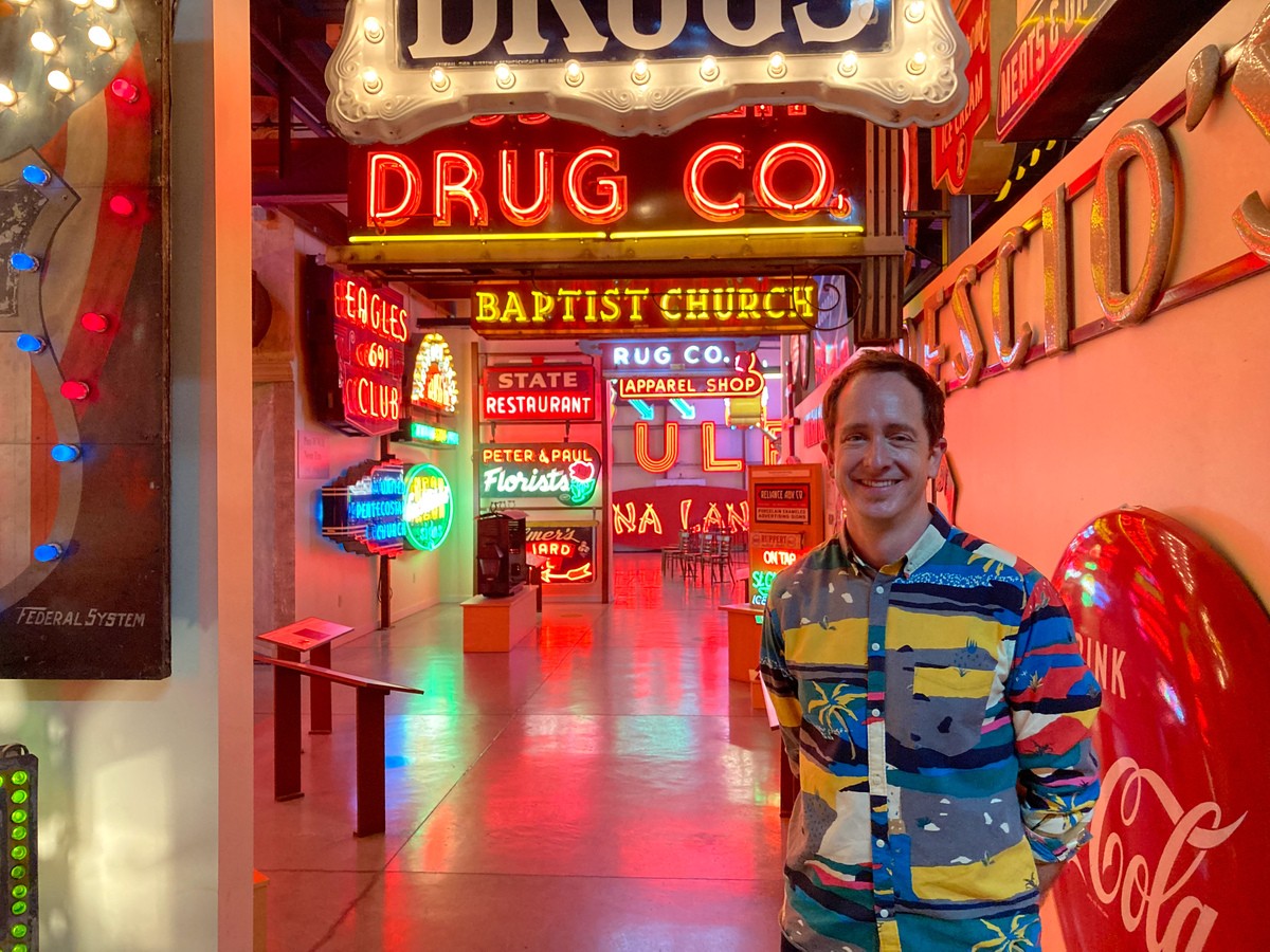 Nathan Morehouse poses with neon signs.