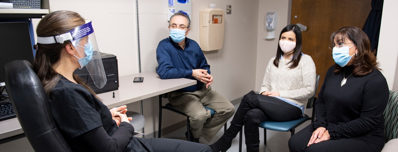 a doctor consults with a man, his daughter and his wife in a consultation room