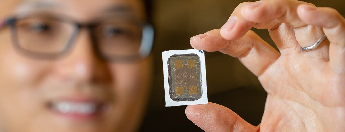 UC assistant professor Yeongin Kim holds up his wearable sensor with one hand in a closeup in front of his face.