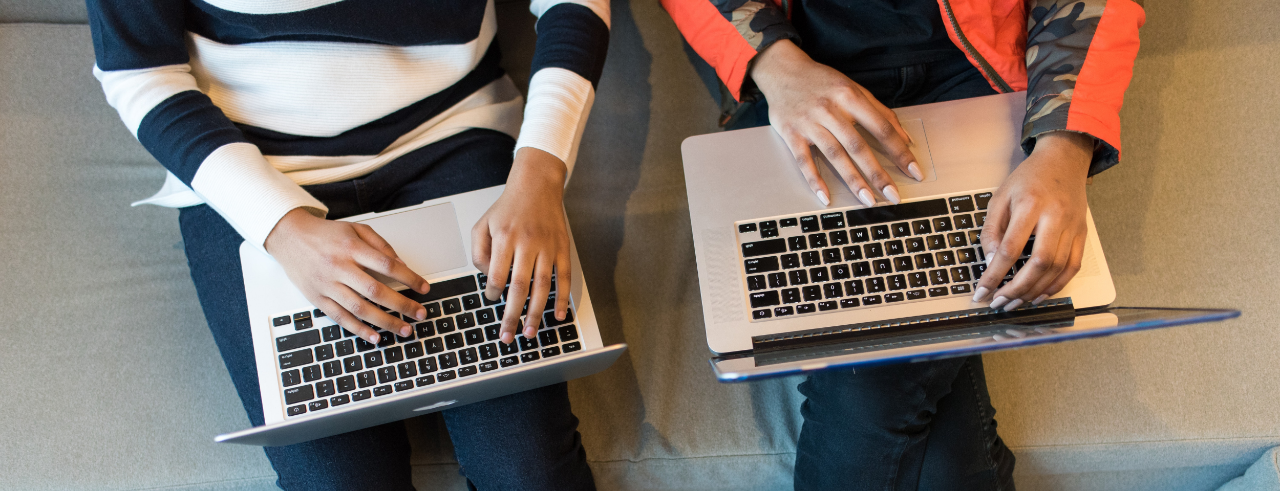 two people type on laptops