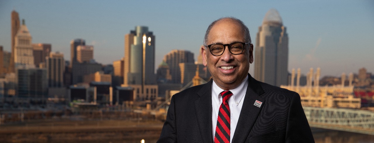 UC President Neville G. Pinto in front of Cincinnati skyline and Ohio River