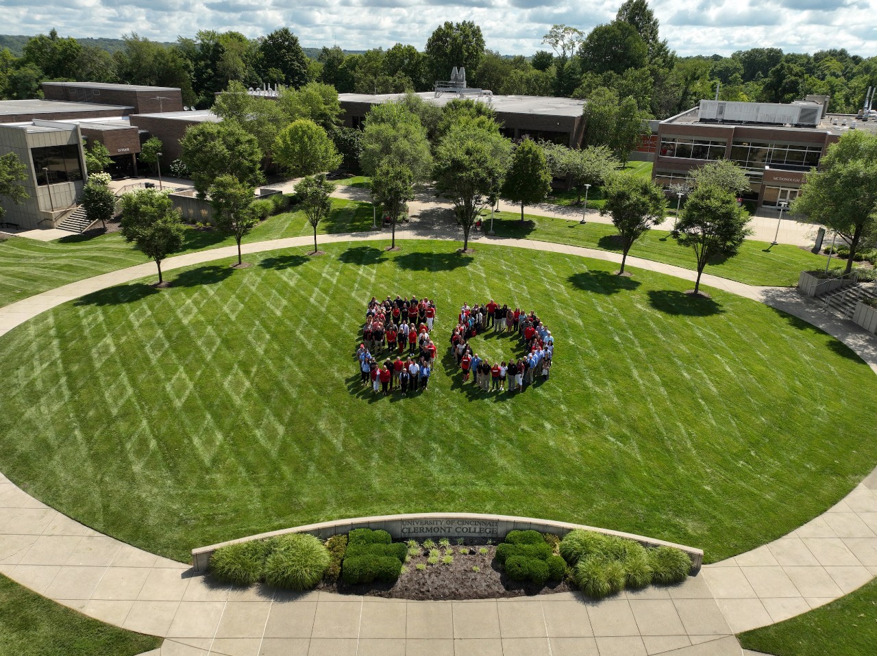 UC Clermont faculty and staff stand in the shape of a "50" on the college campus green