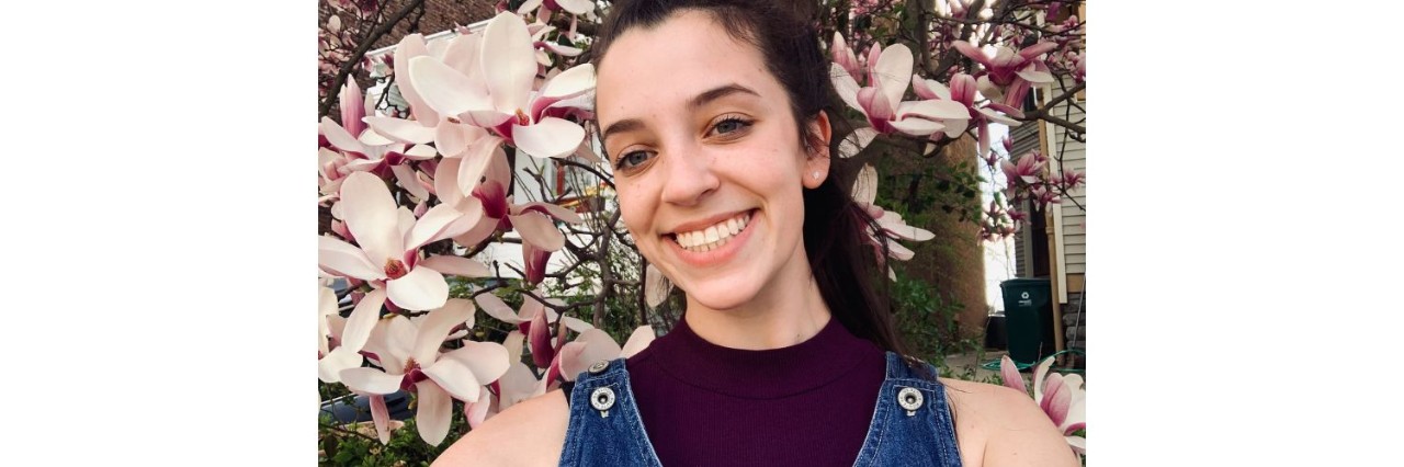 Elizabeth smiling in front of a cherry blossom tree