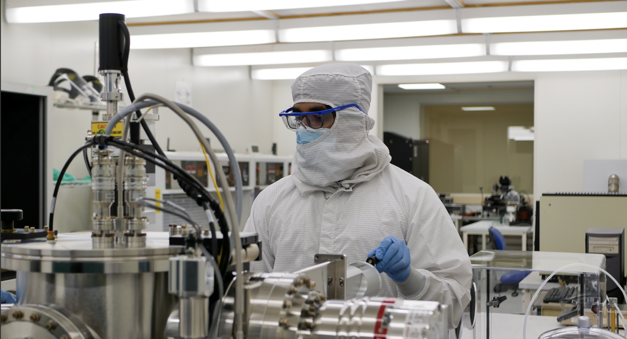 A student works in UC's Clean Room wearing protective equipment from head to toe. 