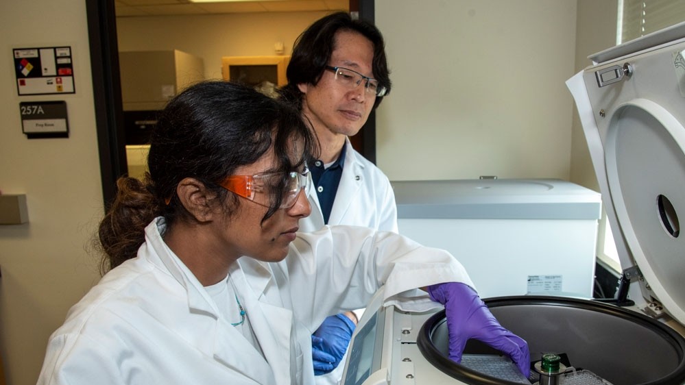 A professor and his female student working with a centrifuge in a lab