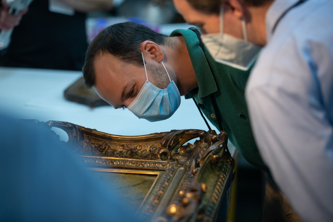 Pietro Strobbia wearing a face mask analyzes a painting.