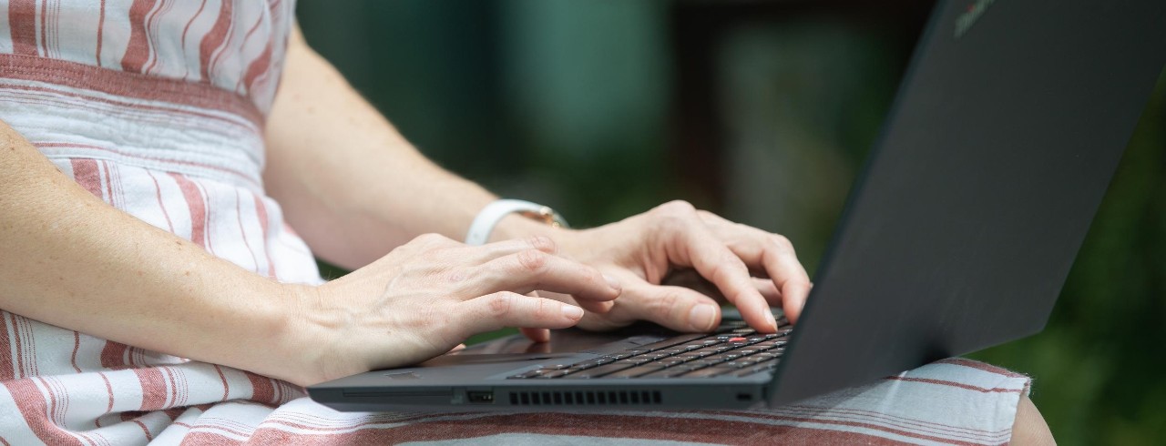 A woman works on a laptop outside.