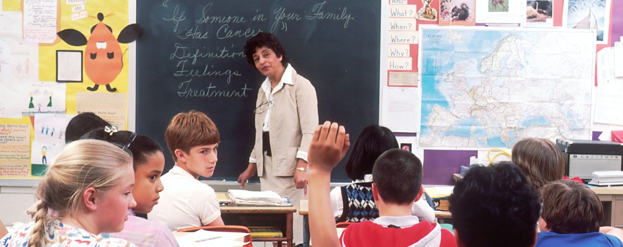 teacher at the white board teaching a class of school children 