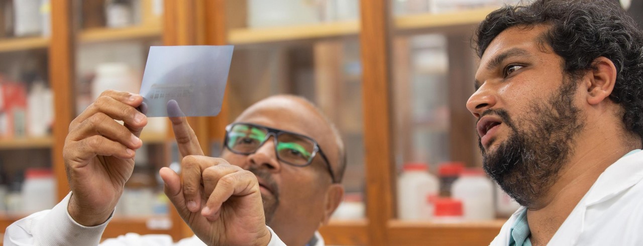 Pankaj Desai points to a sample in the lab while Aniruddha Karve looks on