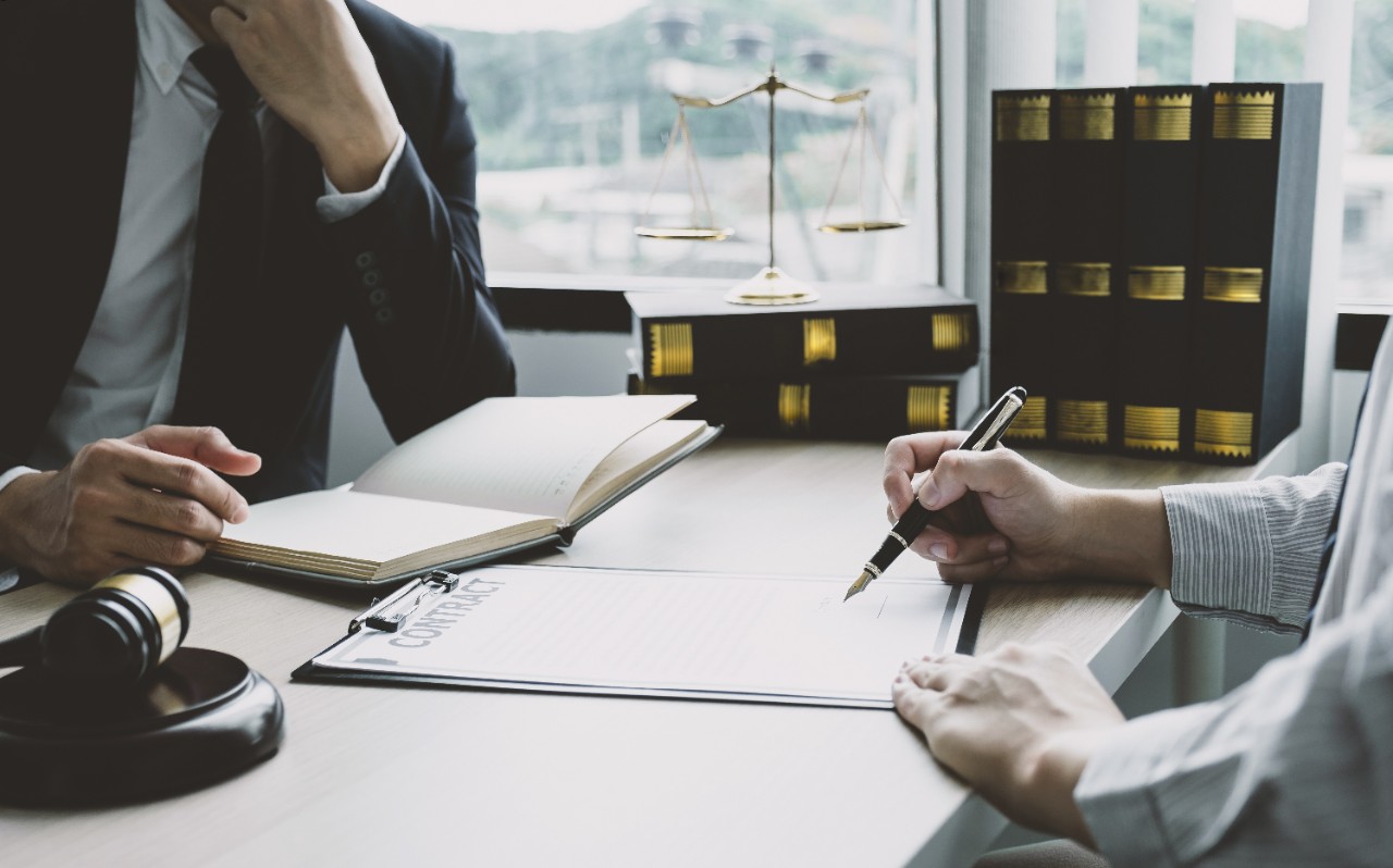 Businessman hand sign contract after lawyer providing legal consult dispute.