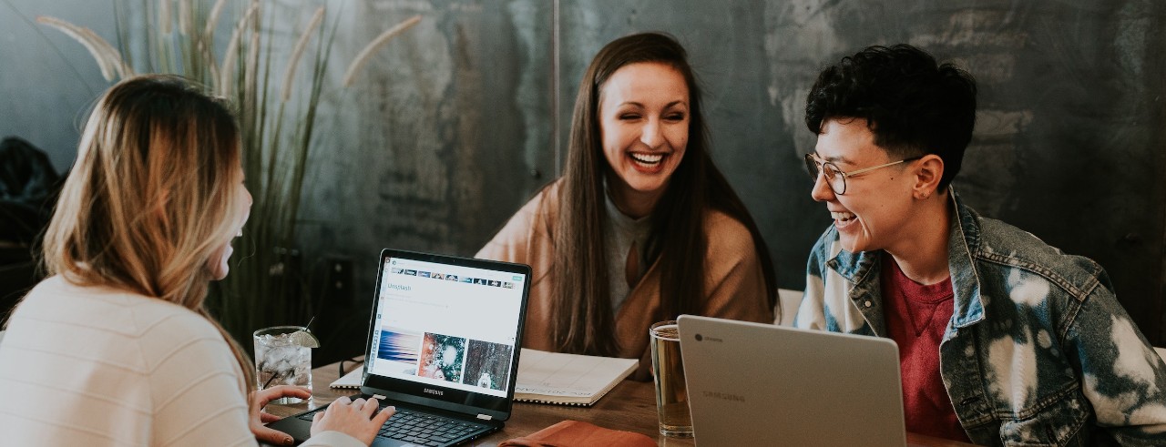 Three people on laptops laughing together