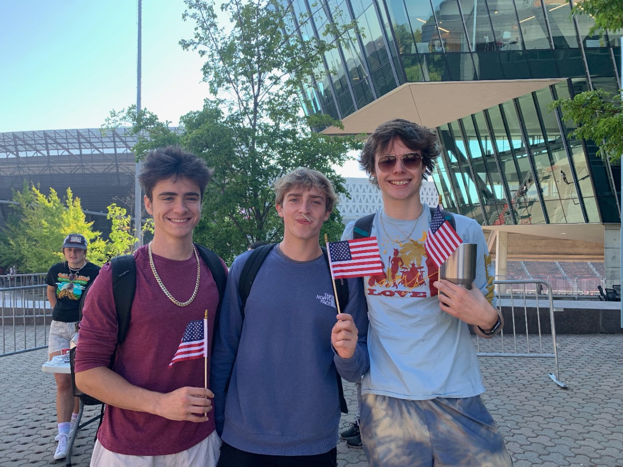 Three UC students holding miniature American flags on campus