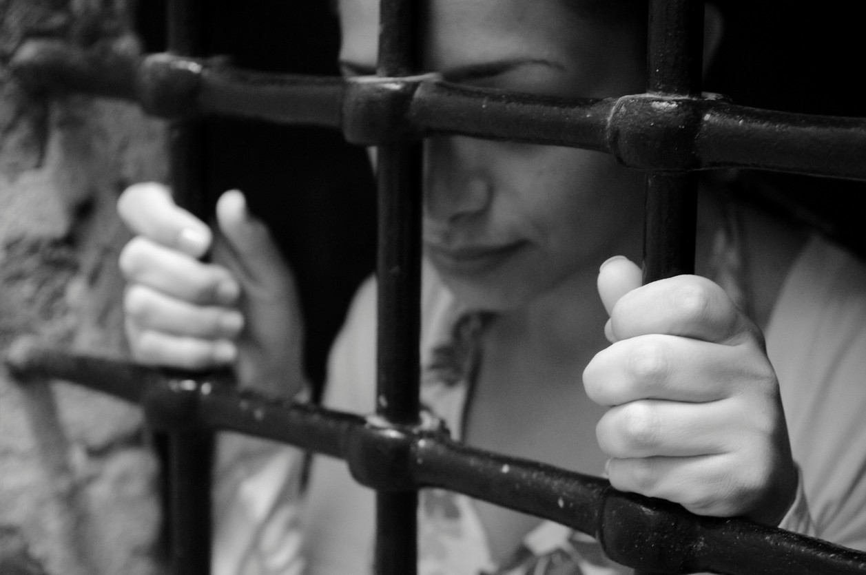 Woman standing behind prison bars