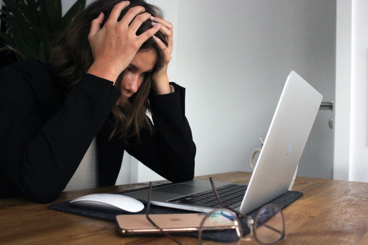 a woman looking stressed sitting in front of her laptop