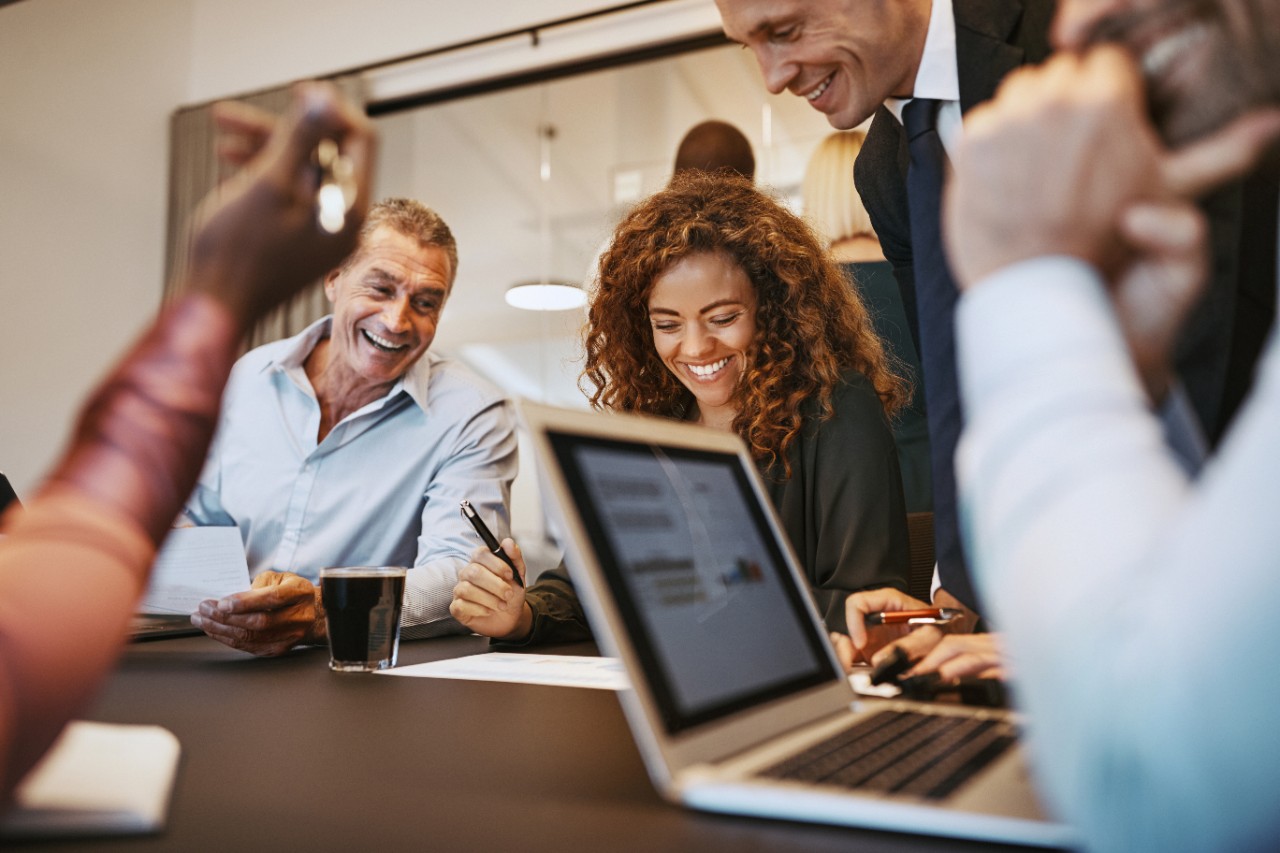 Diverse group of laughing businesspeople sitting together during a meeting around a table in an office boardroom