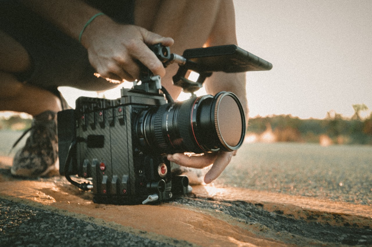 Kneeling person adjusts camera for filming.