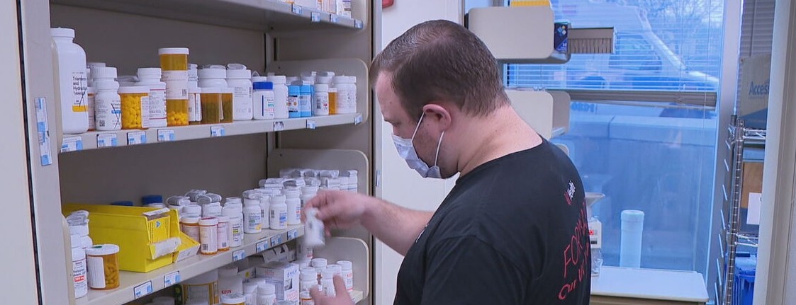 Pharmacy resident Matthew Weaver picks up a prescription bottle off of a shelf