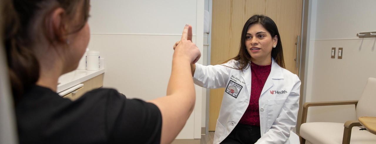 A patient talks and Dr. Mistry press their fingers together in an exam room