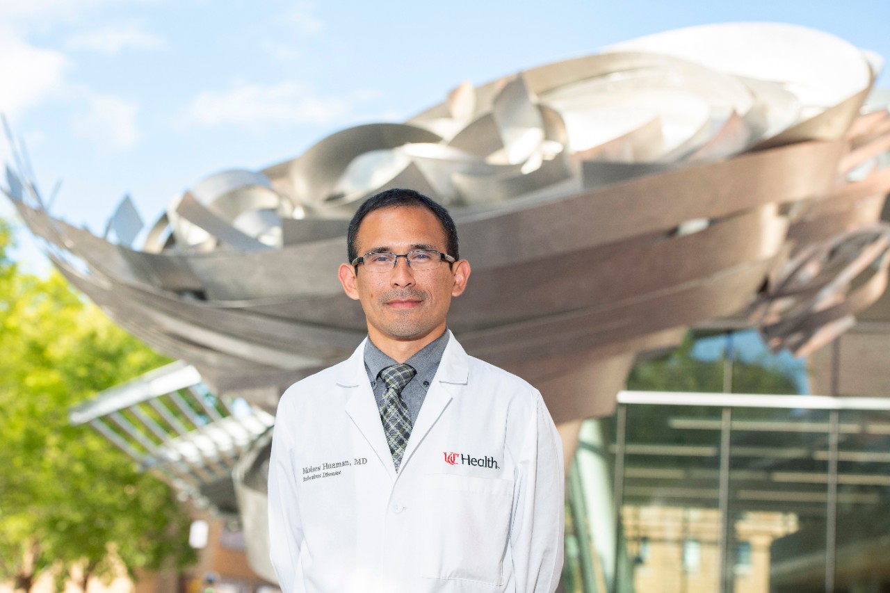 A doctor in a white coat standing in front of a hospital 