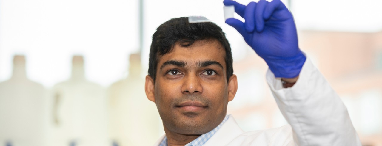 Krushna Patra holds up a slide to the light in his lab