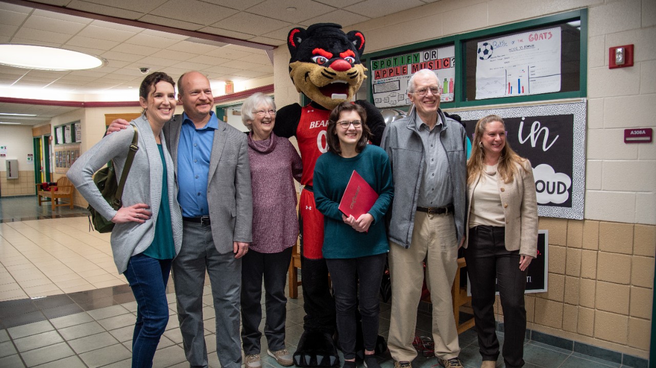 Ava Hartmann with her family and the Bearcat mascot in a school hallway