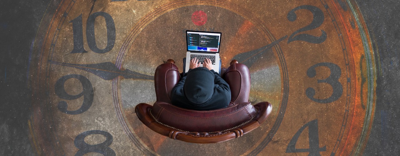 Aerial view of man sitting in chair with laptop over a large clock image on the floor.