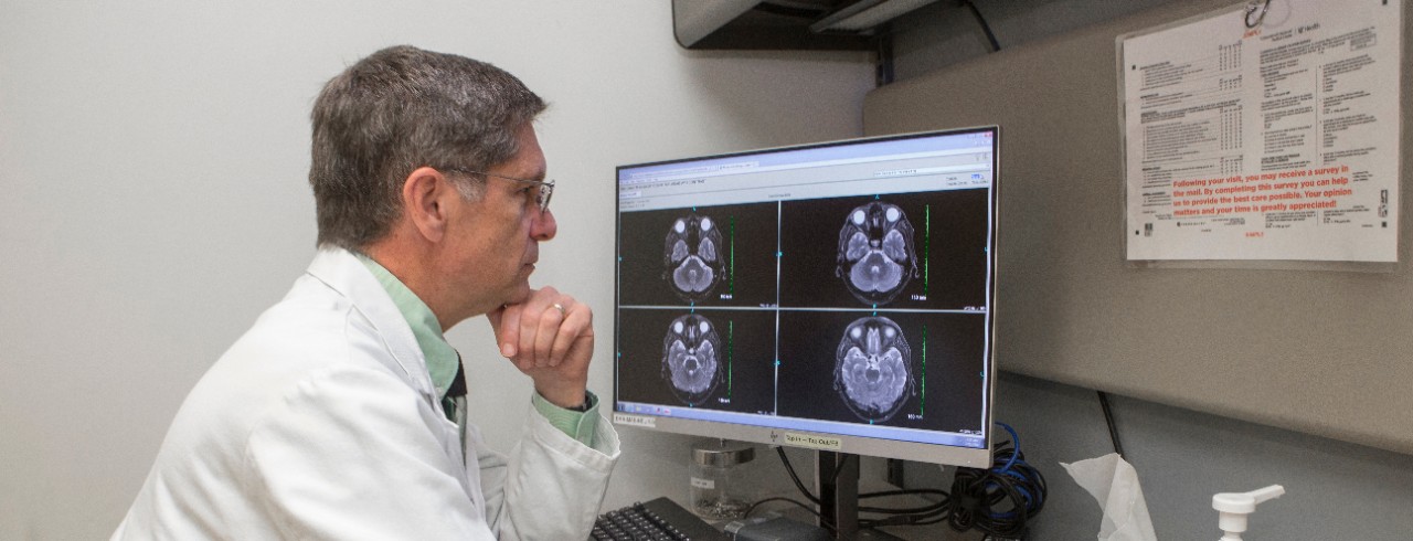Dr. Broderick sits at a desk and examines brain images on a computer screen