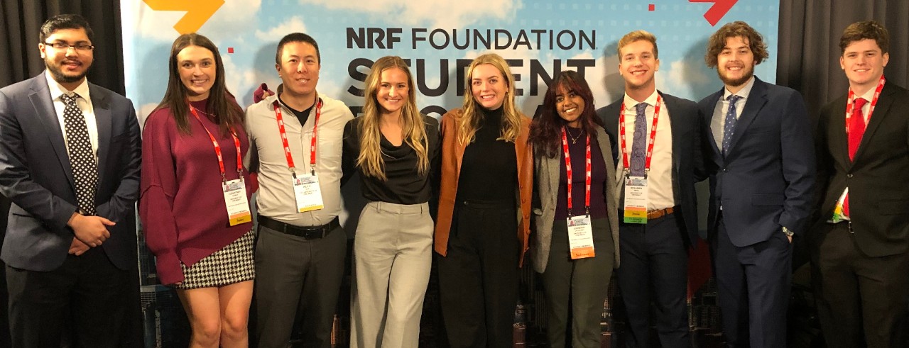 Lindner students and a staff member pose in front of a NRF Foundation Student Program banner.