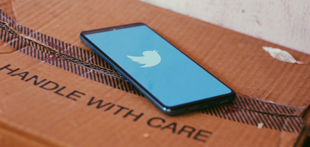Cell phone with Instagram app opened laying on a cardboard box that says: HANDLE WITH CARE.