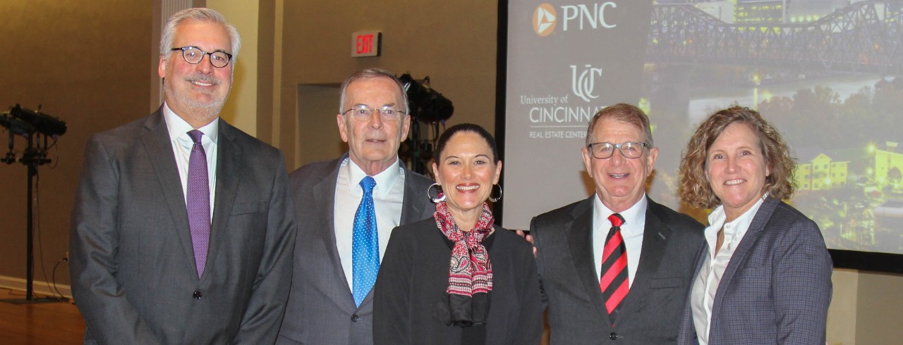 Three men and two women in business professional attire pose for a picture.