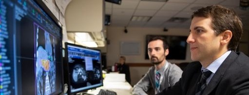 Two doctors sit and review data on a computer screen