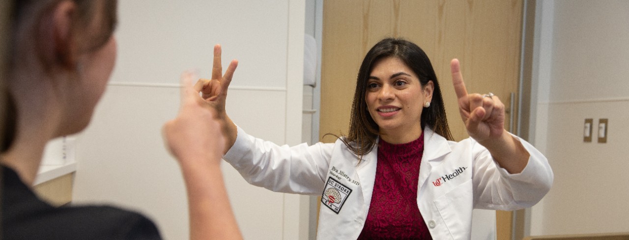Dr. Mistry holds her hands out while a patient points