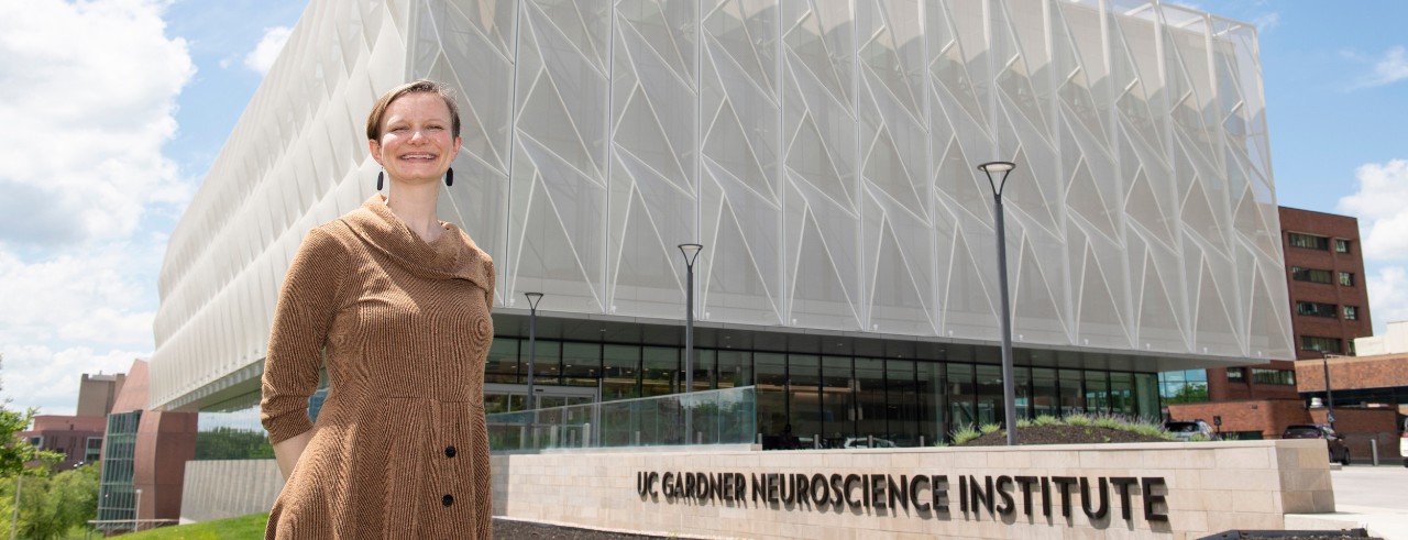 Emily Nurre stands smiling in front of the UC Gardner Neuroscience Institute building