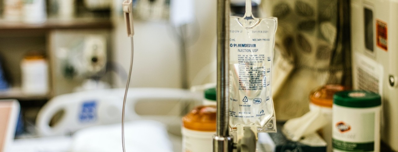 An IV bag of remdesivir is hung in a hospital room