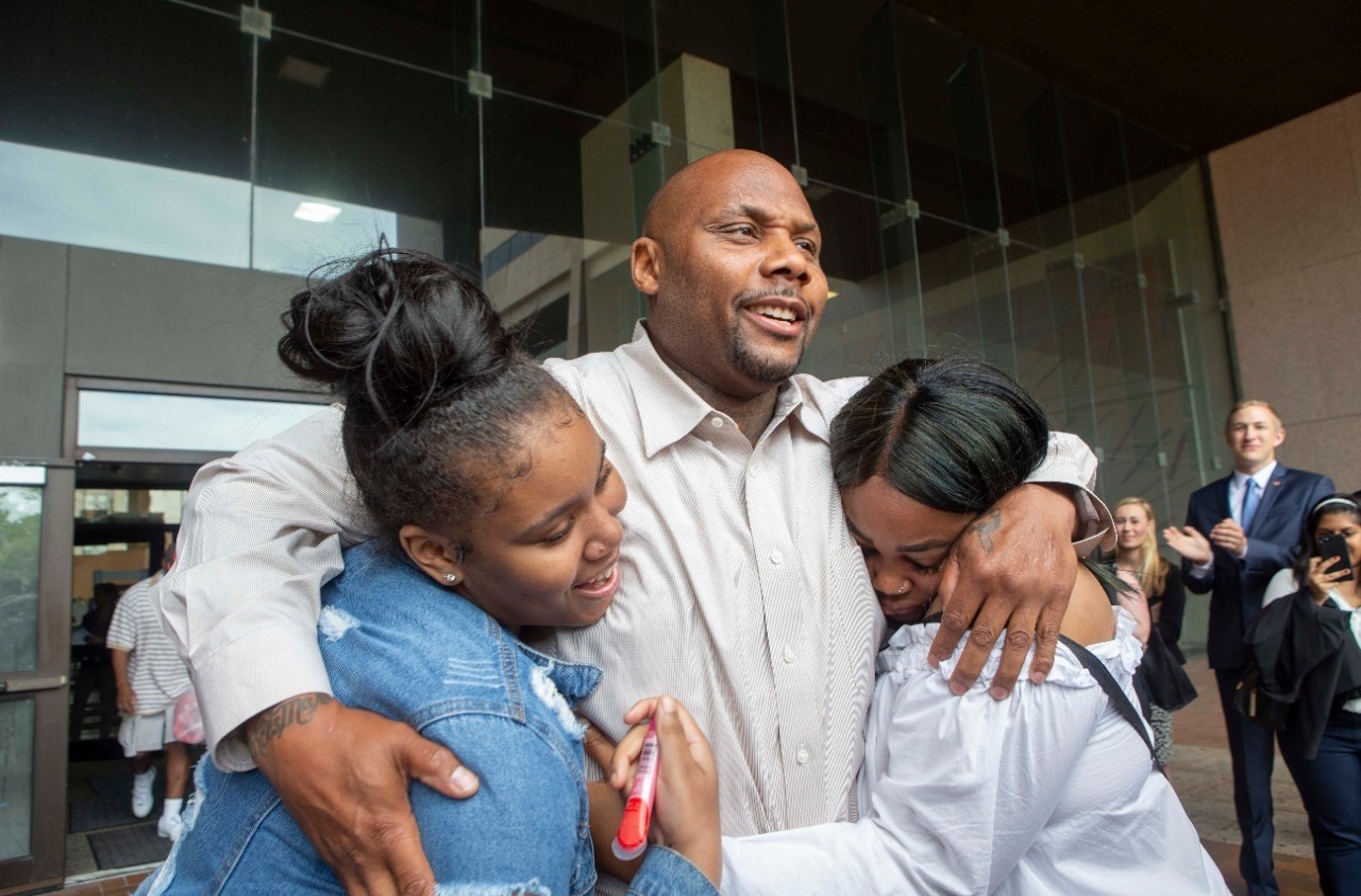 Christopher Miller hugs his daughters De'Nazha, left, and Chareale in 2018 outside the Cuyahoga County Justice Center.