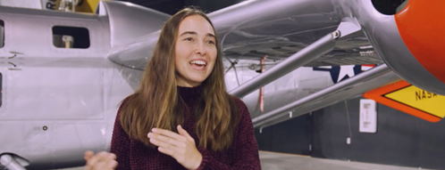 Woman engineering student Lynn Pickering stands in front of an airplane 