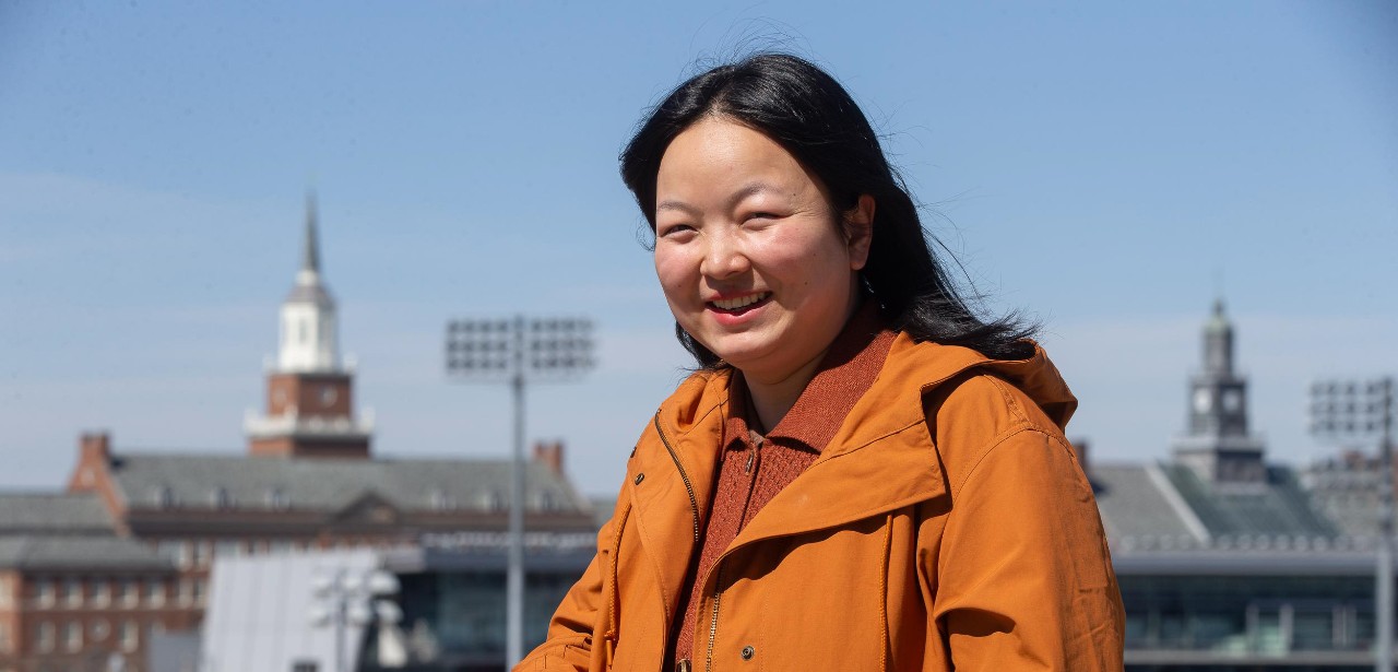 UC doctoral student Man Qi with the UC uptown campus behind her.