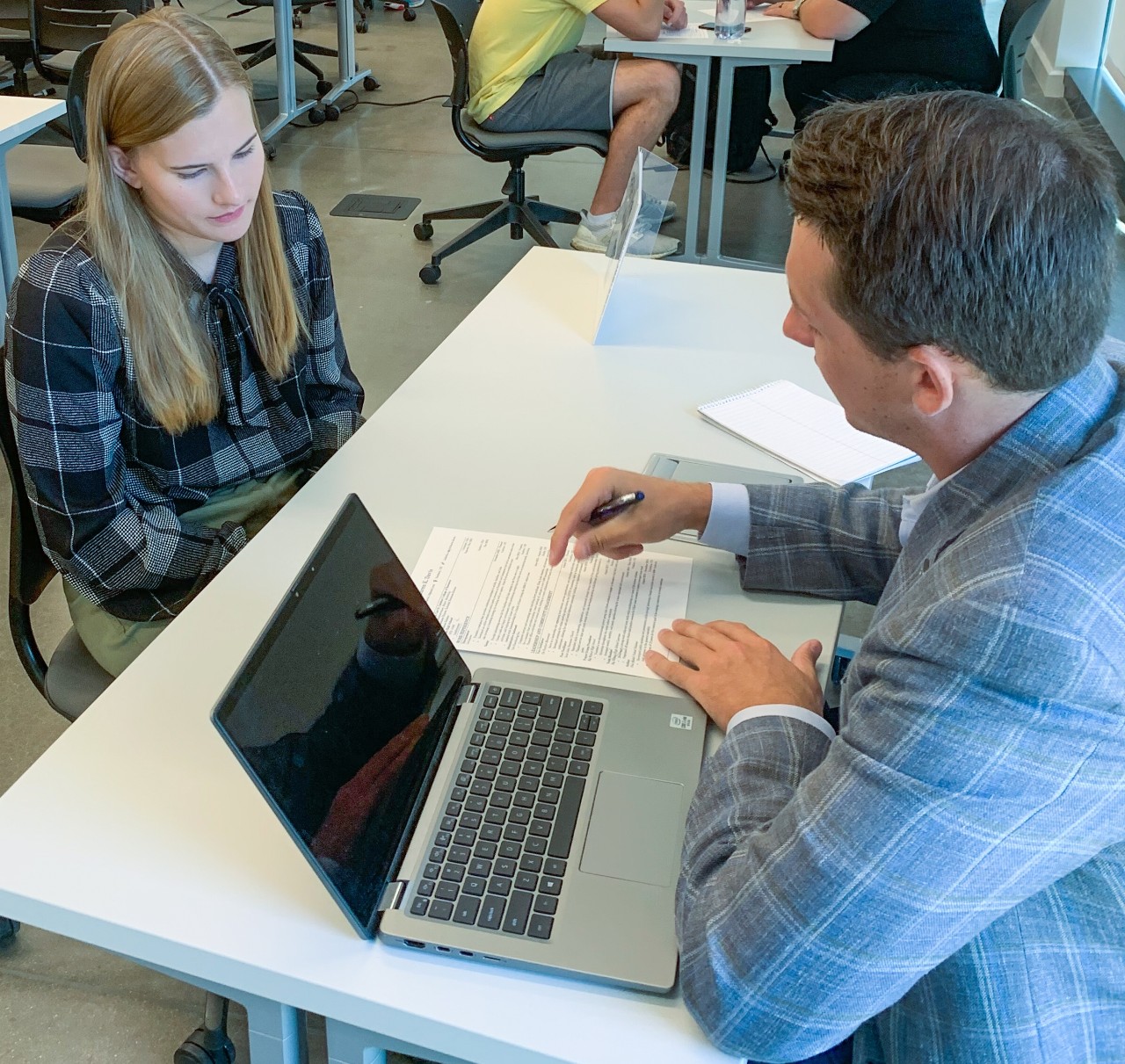 Career services staff member reviews student's resume with female student in Lindner Hall classroom
