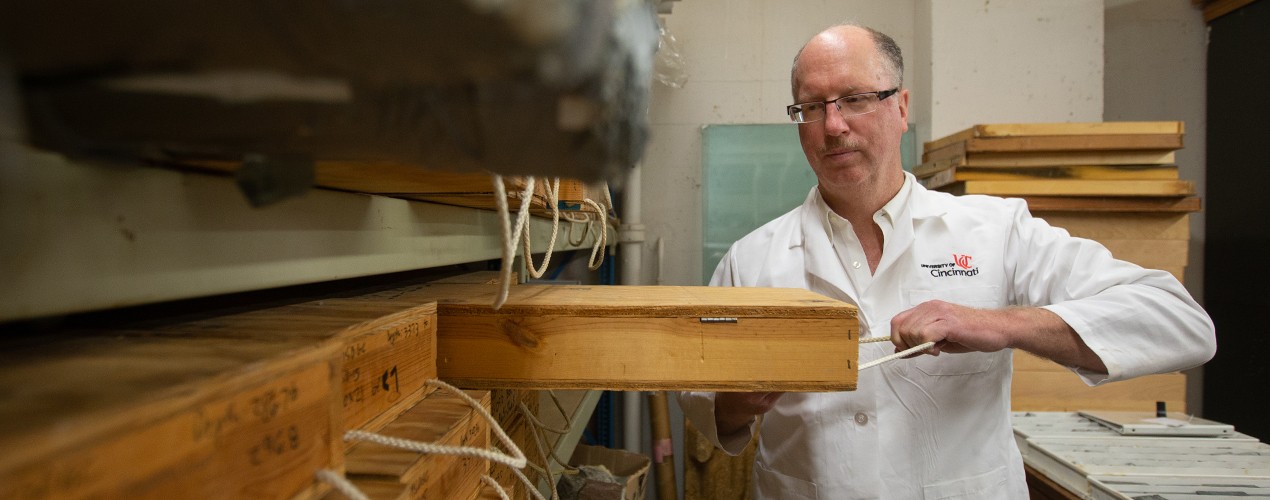 Thomas Algeo pulls geologic specimens in a box off a shelf.