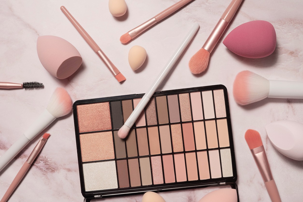 A nude eyeshadow palette and makeup artist's tools on a marble vanity