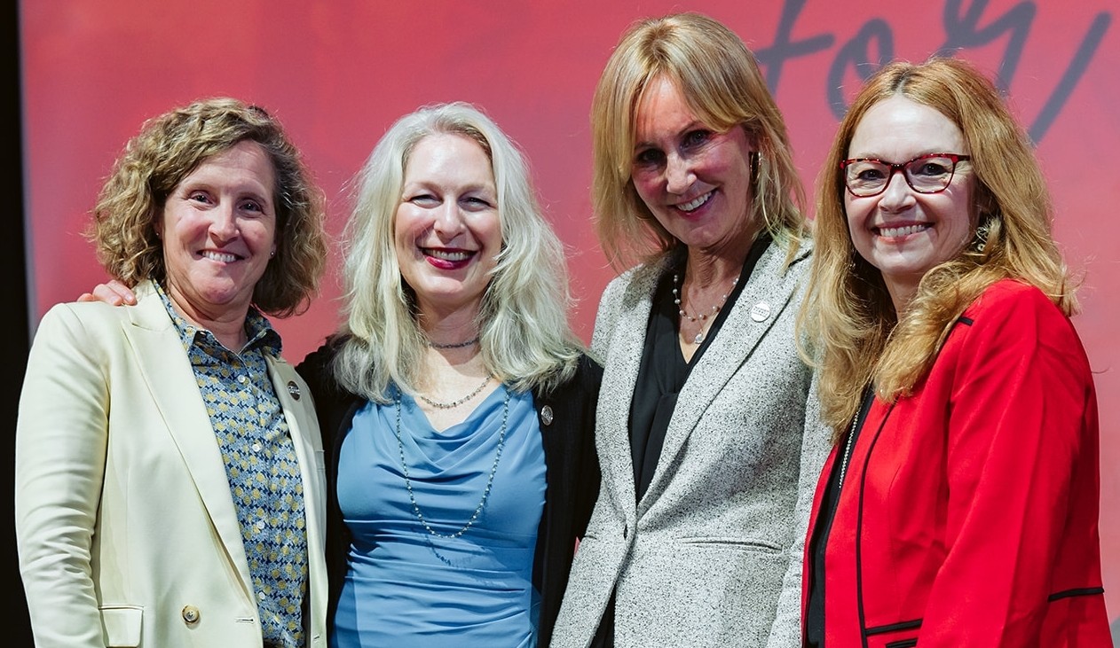 Four women pose on a stage.