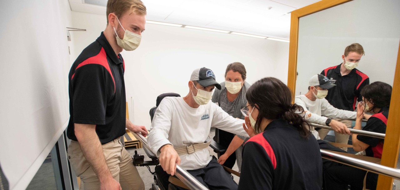 Three students and one faculty member are in office space smiling while tracking patient information. 