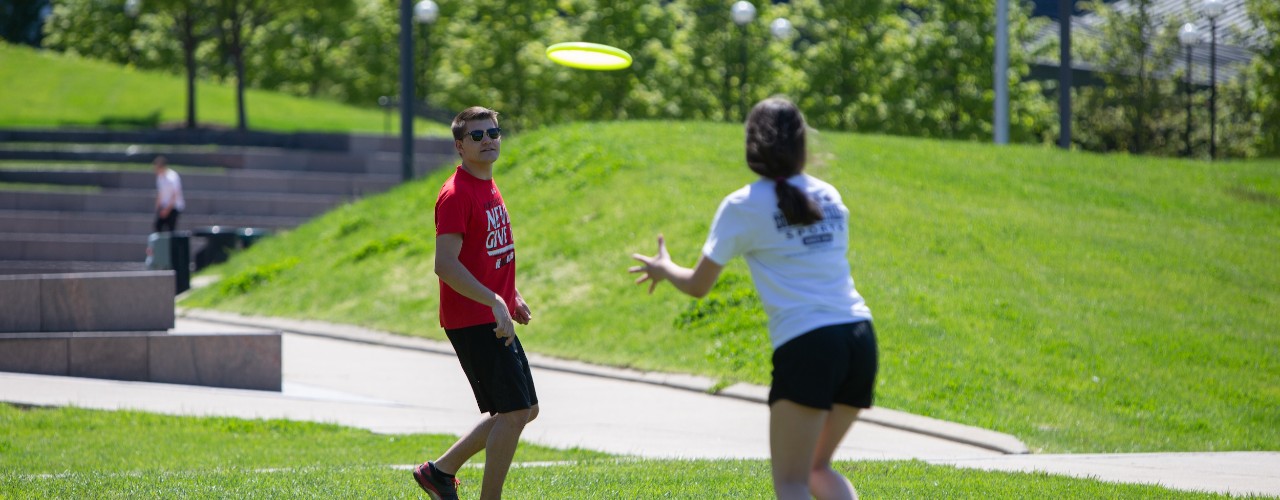 Man and woman play frisbee on UC's Sigma Sigma Commons.