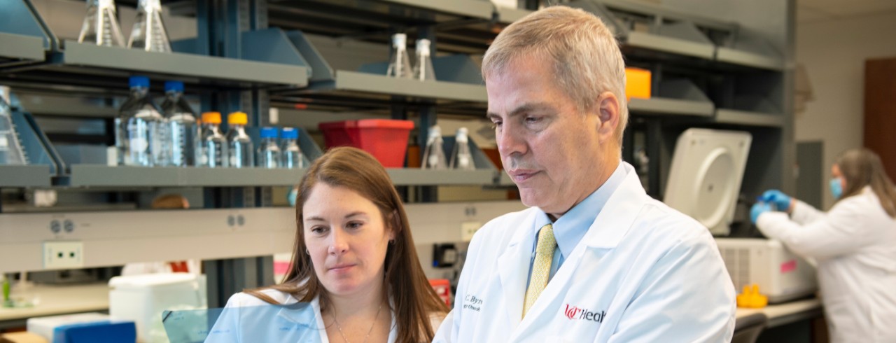 Two doctors in lab coats look at a slide in a laboratory