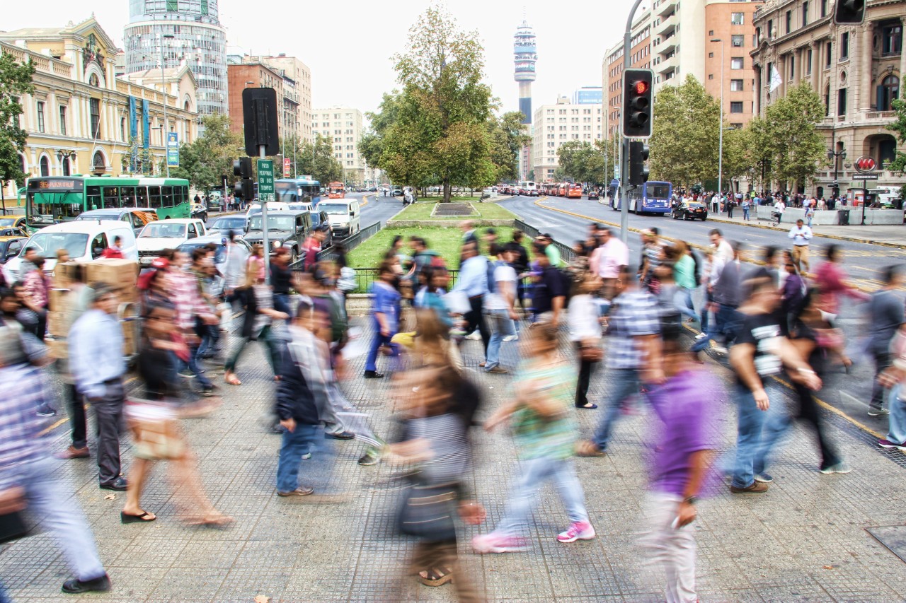 A busy city street is filled with pedestrians crossing the road.