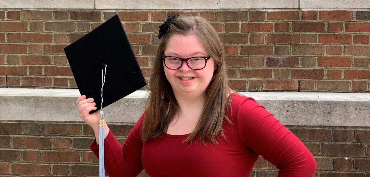 TAP graduate Eve Brennan wearing and red dress and holding a black graduation cap