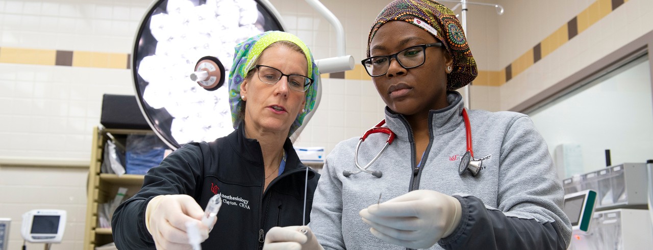 A nursing professor instructs a student in an operating room