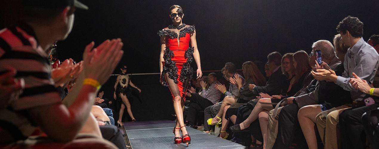 model on runway wearing a red satin dress with black trim for the 2023 DAAP fashion show